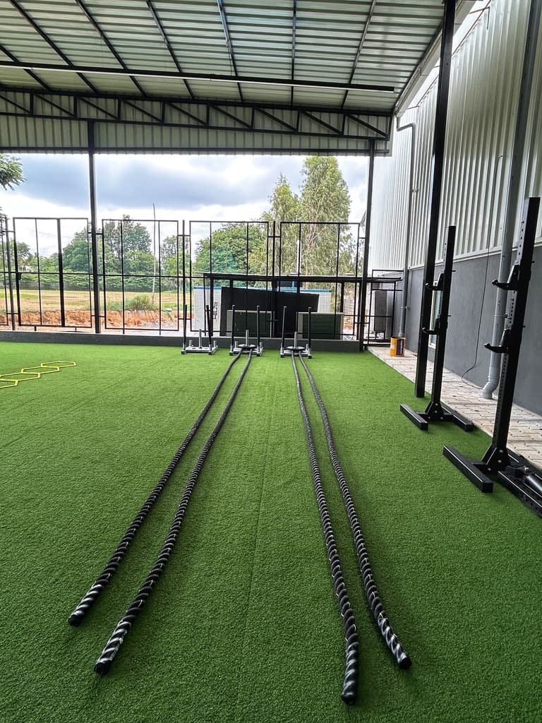 Outdoor turf training area with battle ropes and sleds at FOMO Training